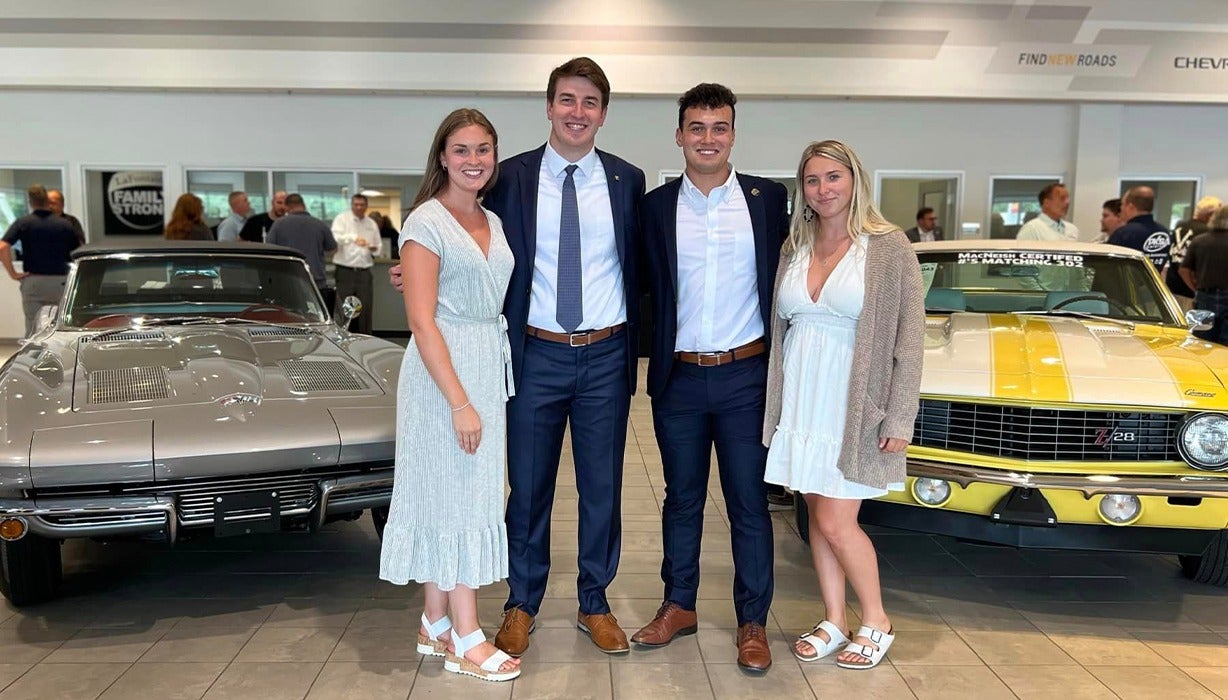image of 4 interns posing in front of 2 cars