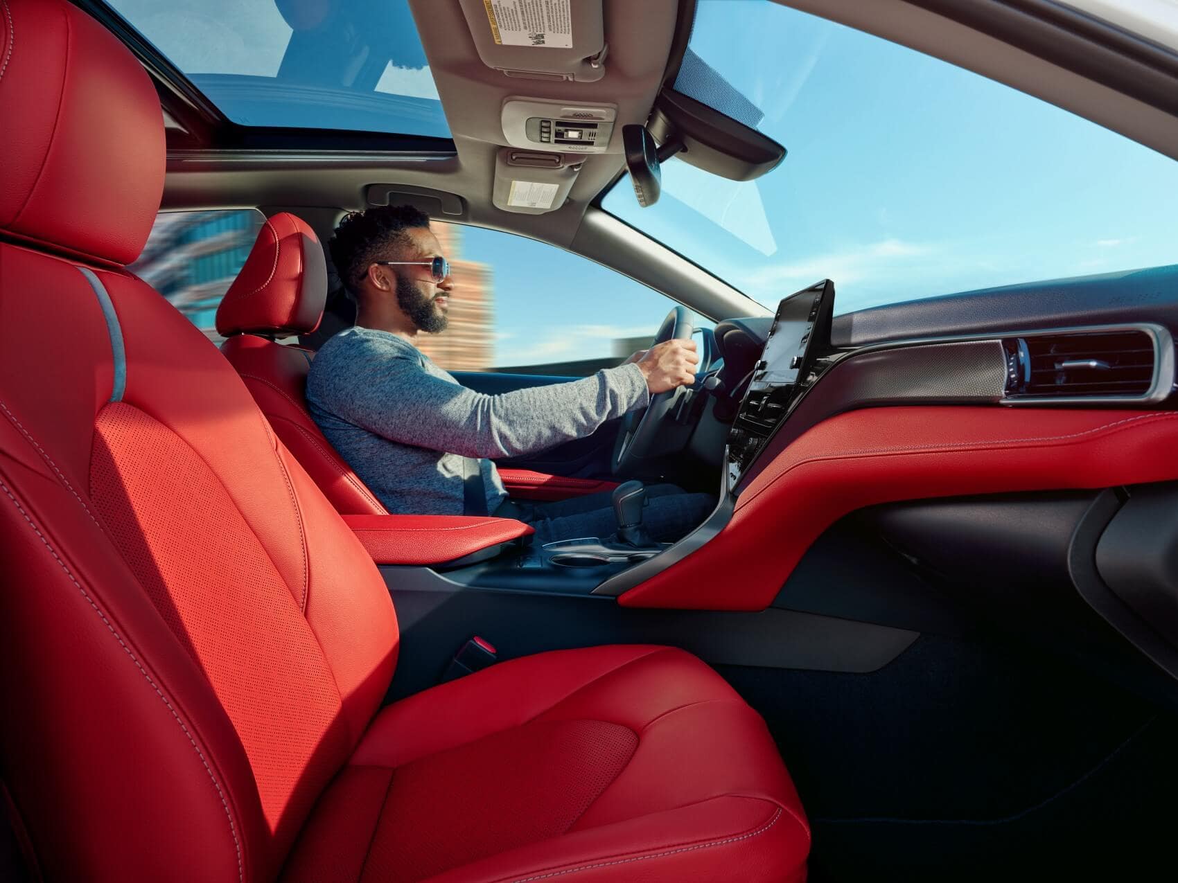 image of a man driving a car with red interior