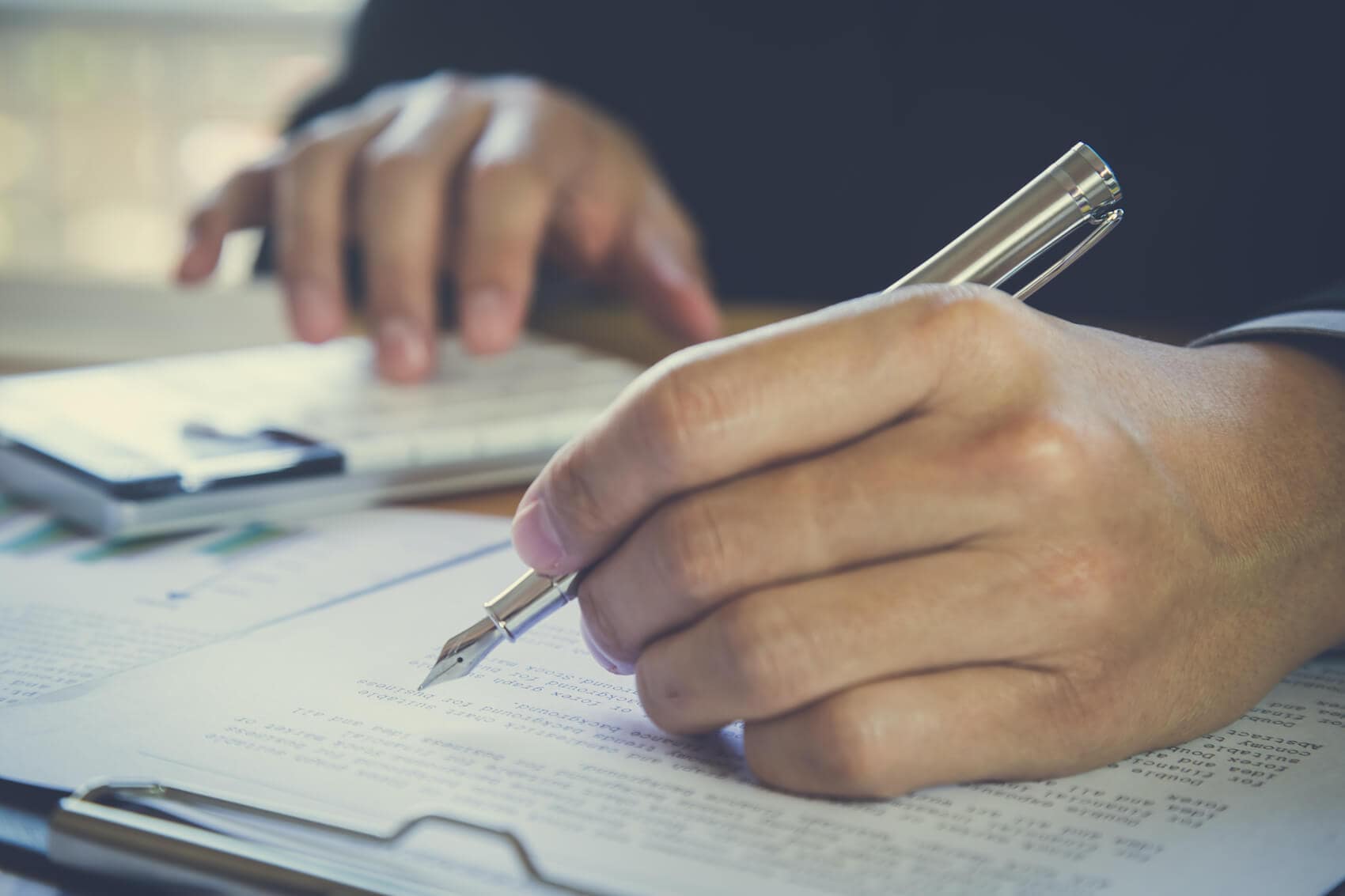 image of someone signing a paper