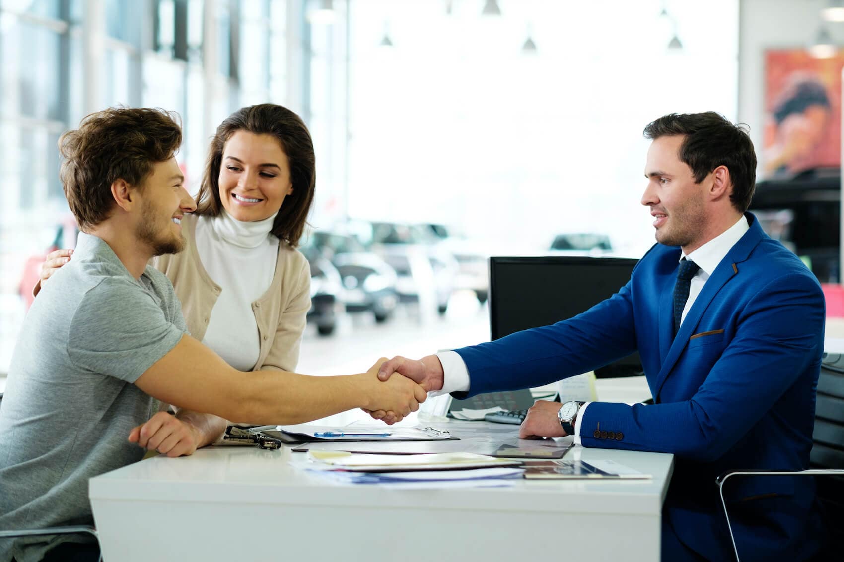 image of 2 men shaking hands and a woman next to one of them