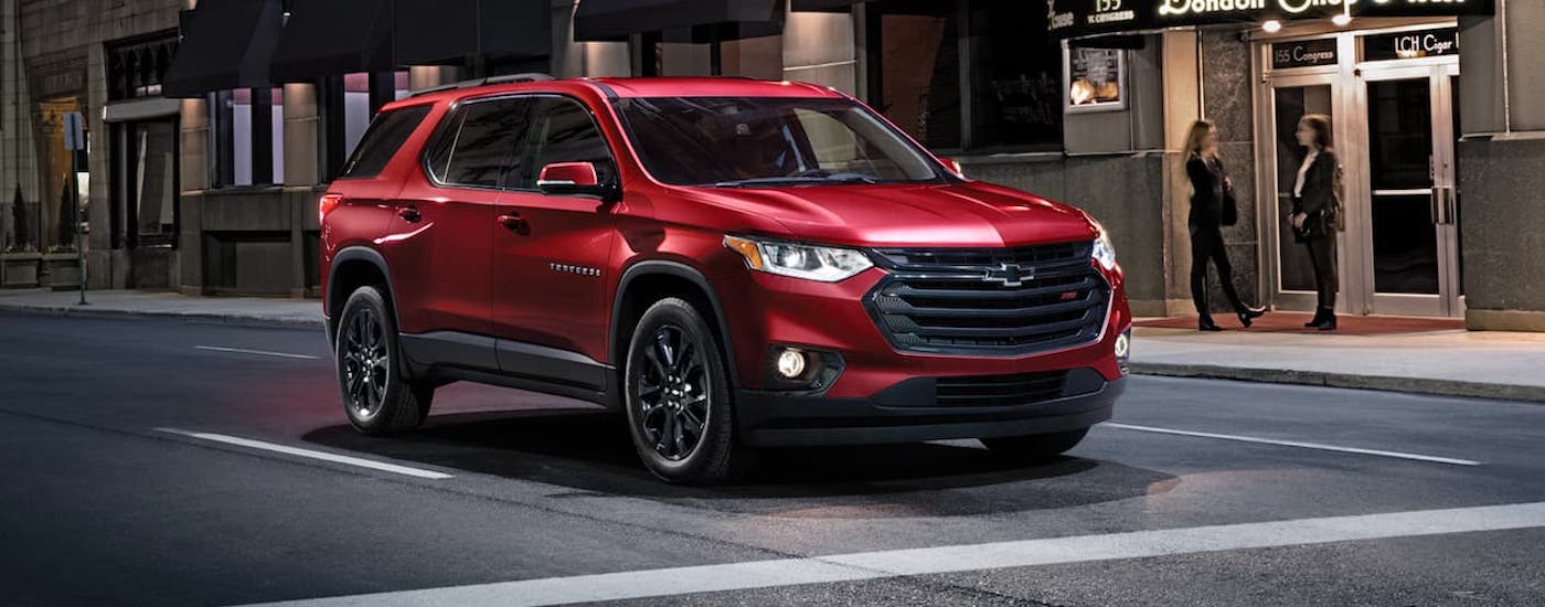 Red 2020 Chevy Traverse RS driving down a city street.