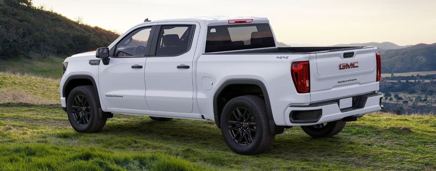 White 2024 GMC Sierra 1500 from the side parked in the grass.