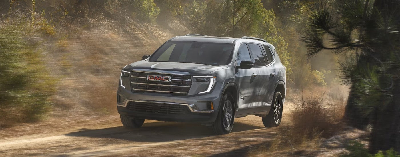 Grey 2025 GMC Acadia driving off-road.