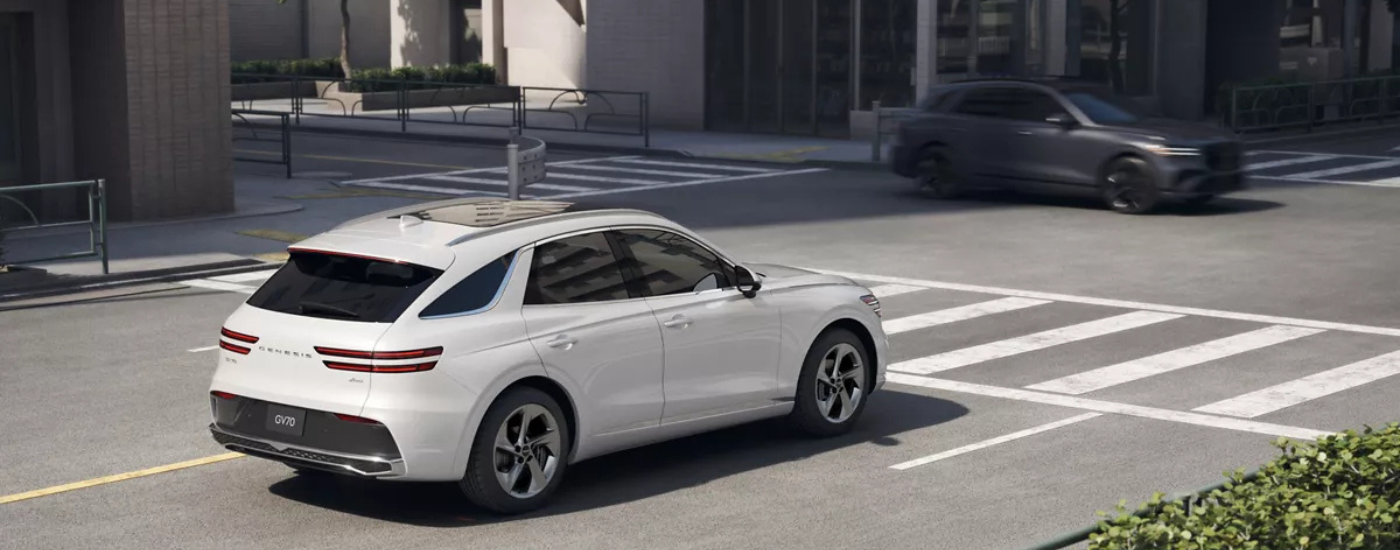 White 2024 Genesis GV70 driving through a city