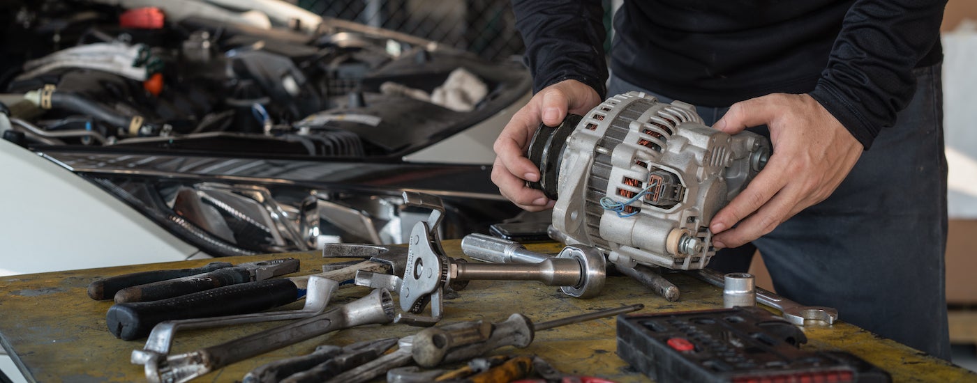 Mechanic holding an alternator.
