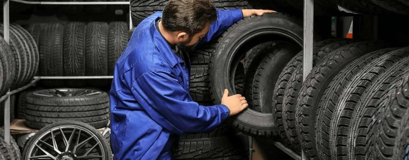 Mechanic pulling a tire off of a rack.