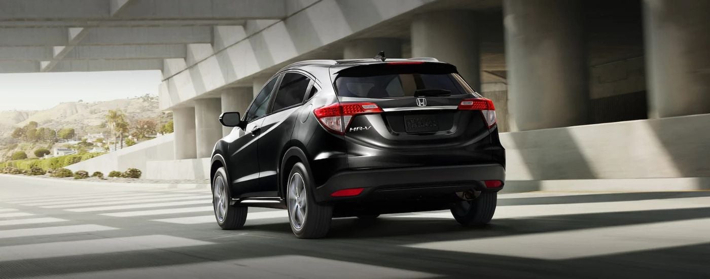 Rear of a black 2021 Honda HR-V driving under a bridge.